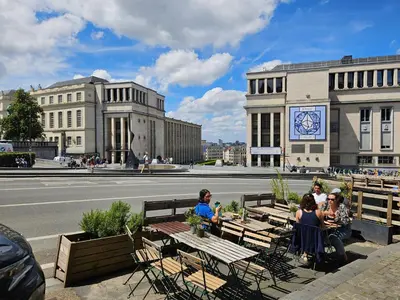 a group of people sitting at tables on the side of a street at Centre de Bruxelles Merveilleux ! in Brussels