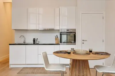 a kitchen with a wooden table and white cabinets at 1-BR Centre Antwerp Haven with Patio in Antwerp