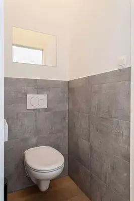 a bathroom with a white toilet and a window at 1-BR Centre Antwerp Haven with Patio in Antwerp