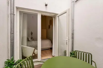 a green table and chairs on a balcony with a bedroom at 1-BR Centre Antwerp Haven with Patio in Antwerp