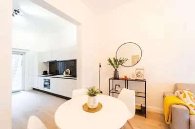 a white living room with a table and a couch at Your Antwerp Adventure Sleeps 4 in Antwerp