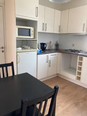 a kitchen with white cabinets and a table and a microwave at Bright appartement in Zaventem