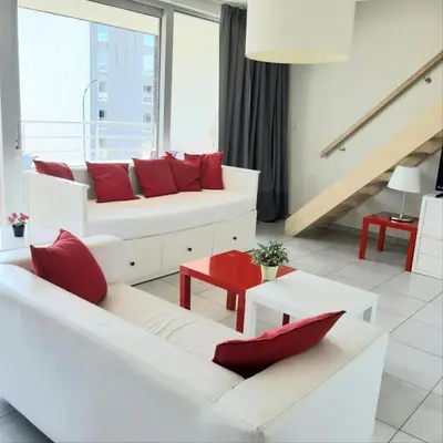 a living room with two white couches and red pillows at Brussels Base Camp in Brussels