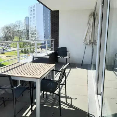a balcony with a wooden table and chairs on it at Brussels Base Camp in Brussels