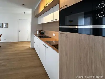 a kitchen with white cabinets and black appliances at Vakantiewoning Erf64 in Sint-Amands