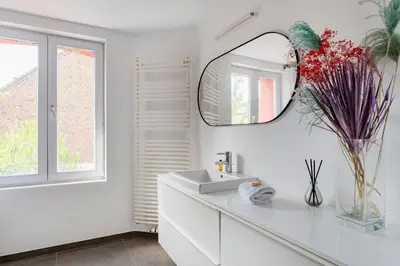 a white bathroom with a sink and a mirror at Brussels Flagey Elegant in Brussels