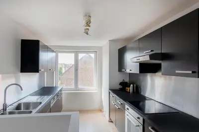 a kitchen with black and white cabinets and a window at Brussels Flagey Elegant in Brussels