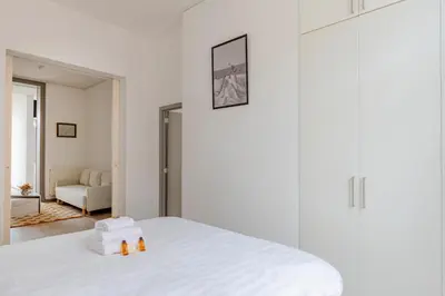 a white bedroom with a white bed with two candles on it at Brussels Flagey Elegant in Brussels