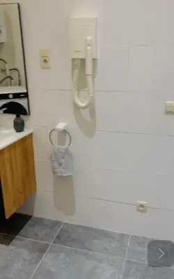 a bathroom with a sink and a phone on the wall at Quarto da Nessa próximo a Louise in Brussels