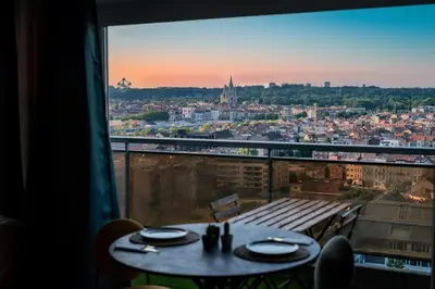 a table with a view of a city from a window at Studio avec vue panoramique et parking gratuit in Brussels