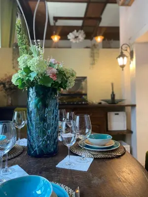 a table with a vase with flowers and plates and glasses at Magical double bedroom duplex in Brussels