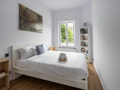 a white bedroom with a white bed with a teddy bear on it at Brussels Toison D'or residence in Brussels