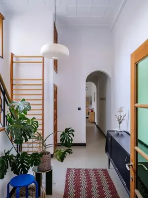 a hallway with two plants and a blue chair and a table at Art-deco woning Gent in Ghent