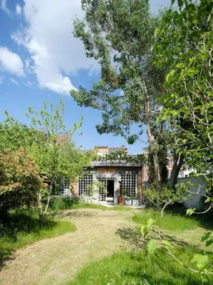 a house in the middle of a yard with trees at Art-deco woning Gent in Ghent