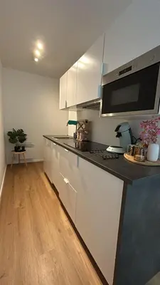 a kitchen with white cabinets and a black counter top at Chez soi in Brussels