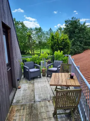 a patio with a wooden table and chairs on a deck at Het Horzelend, oase van rust in een fietsparadijs in Retie