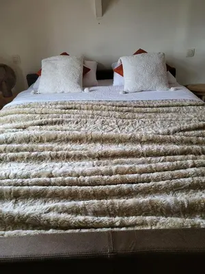 a bed with a brown and white blanket on it at Het Horzelend, oase van rust in een fietsparadijs in Retie