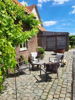 a patio with chairs and a table in front of a building at Het Horzelend, oase van rust in een fietsparadijs in Retie