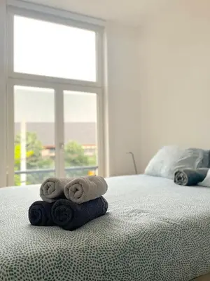 a stack of towels on a bed with a window at Apartment in the Heart of Ghent with Fantastic Views in Ghent