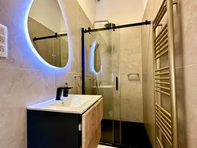 a bathroom with a sink and a shower with a mirror at Luxury Suits Royal by Rikas Hotels in Antwerp