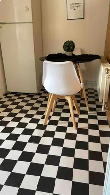a table and a white chair on a checkered floor at Cosy place near Atomium with parking in Vilvoorde