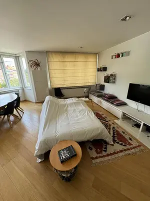 a bedroom with a bed and a table and a tv at Appartement Ixelles 2 chambres, 3 lits in Brussels