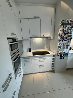 a white kitchen with white cabinets and a refrigerator at Appartement Ixelles 2 chambres, 3 lits in Brussels