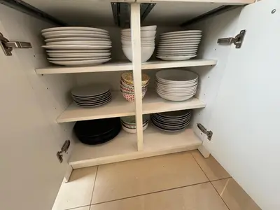 a cupboard filled with white plates and bowls at Appartement Ixelles 2 chambres, 3 lits in Brussels