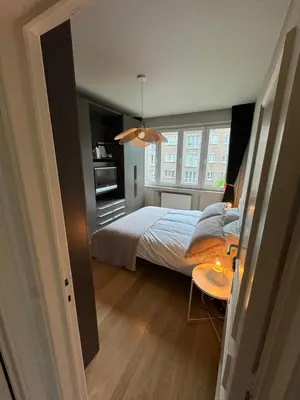 a bedroom with a bed and a table and a window at Appartement Ixelles 2 chambres, 3 lits in Brussels