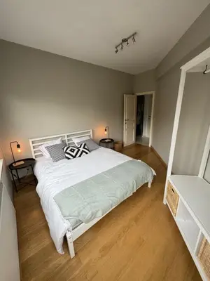 a bedroom with a large white bed and wooden floors at Appartement Ixelles 2 chambres, 3 lits in Brussels