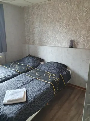 two twin beds in a room with a wall at De Baolse Herberg in Baarle-Hertog
