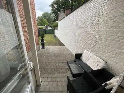 a patio with a bench next to a brick wall at E&L Appartement in Willebroek