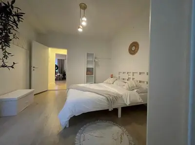a white bedroom with a bed and a clock on the wall at E&L Appartement in Willebroek