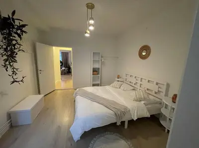 a white bedroom with a large bed and a hallway at E&L Appartement in Willebroek