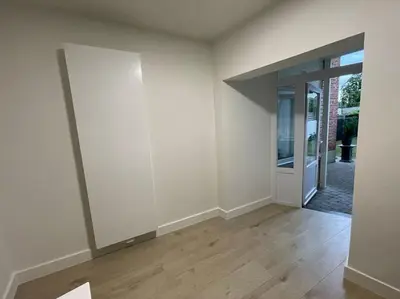 an empty room with white walls and wooden floors at E&L Appartement in Willebroek