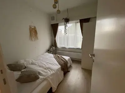 a small bedroom with a bed and a window at E&L Appartement in Willebroek