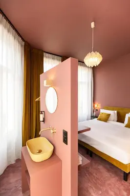 a pink hotel room with a bed and a sink at The Mila Hotel in Brussels