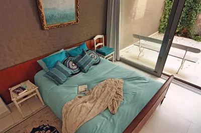 a bedroom with a bed with blue sheets and pillows at Lounge in the Intimate Urban Garden at a Retro Getaway in Ghent