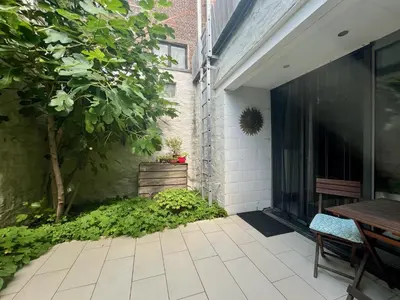 an outdoor patio with a table and a tree at Lounge in the Intimate Urban Garden at a Retro Getaway in Ghent