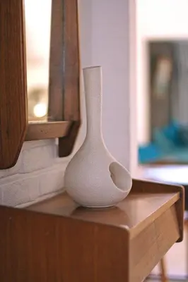 a white vase sitting on top of a wooden table at Lounge in the Intimate Urban Garden at a Retro Getaway in Ghent