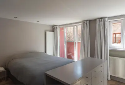 a bedroom with a bed and a desk and a window at Flagey Terrace Design residence in Brussels