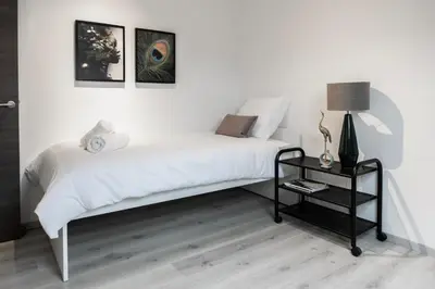 a bedroom with a white bed and a black table at Unique Parking access, XL home w Parking option in Antwerp