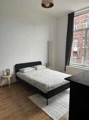 a bedroom with a bed and a large window at Studio Issa in Brussels