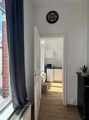 an open door to a kitchen with a clock on the wall at Studio Issa in Brussels