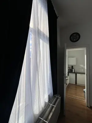 a window with a white curtain in a room at Studio Issa in Brussels