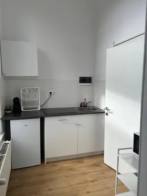 a kitchen with white cabinets and a black counter top at Studio Issa in Brussels