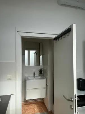 a white bathroom with a sink and a mirror at Studio Issa in Brussels