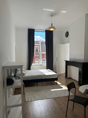 a bedroom with a bed and a desk and a window at Studio Issa in Brussels