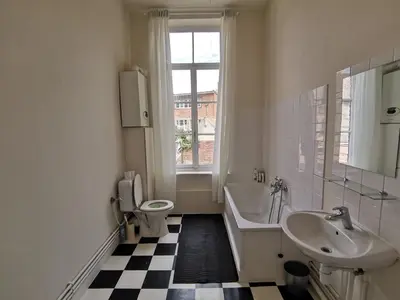 a bathroom with a sink and a toilet and a tub and a window at Private room near Gravensteen in Ghent