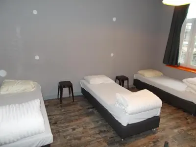 a room with three beds and a window at Urban City Centre Hostel in Brussels